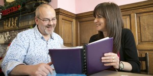 Two people working together, smiling looking at a book