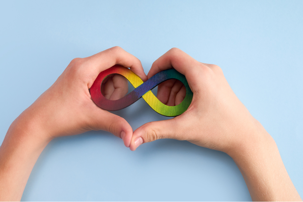 Two hands holding the rainbow infinity neurodivergent symbol